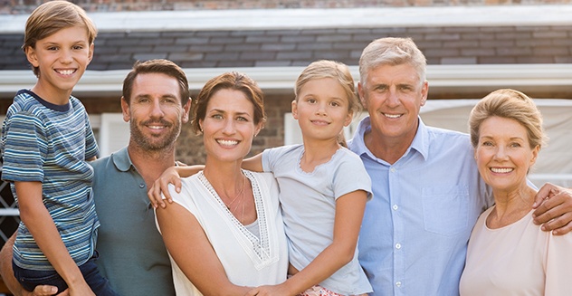 family of 6 smiling outside of house