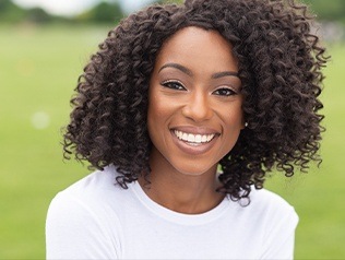 woman in white with curly hair smiling