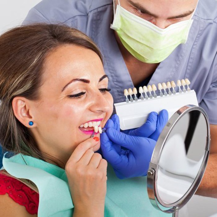 woman with red shirt trying on veneers in dental chair 