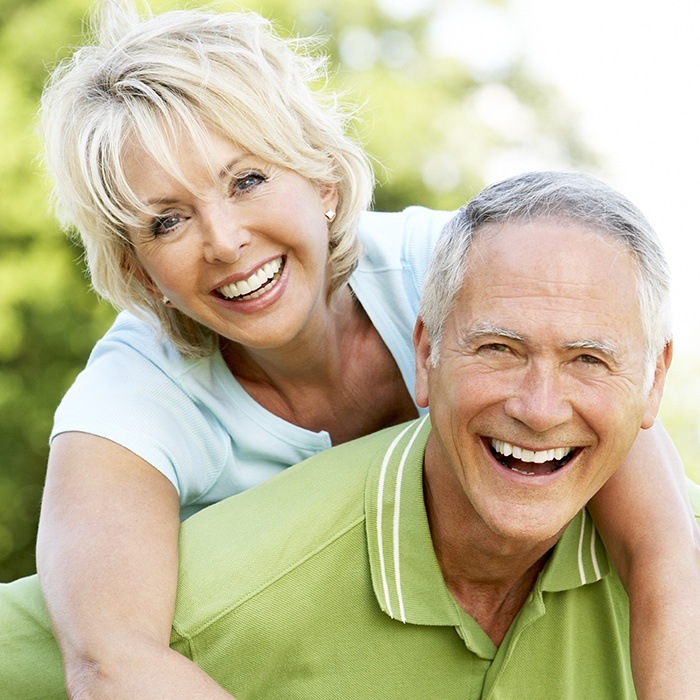 man giving woman piggyback ride and smiling after visiting cosmetic dentist in Charlottesville