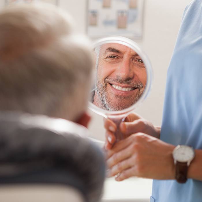 man looking into circle mirror smiling