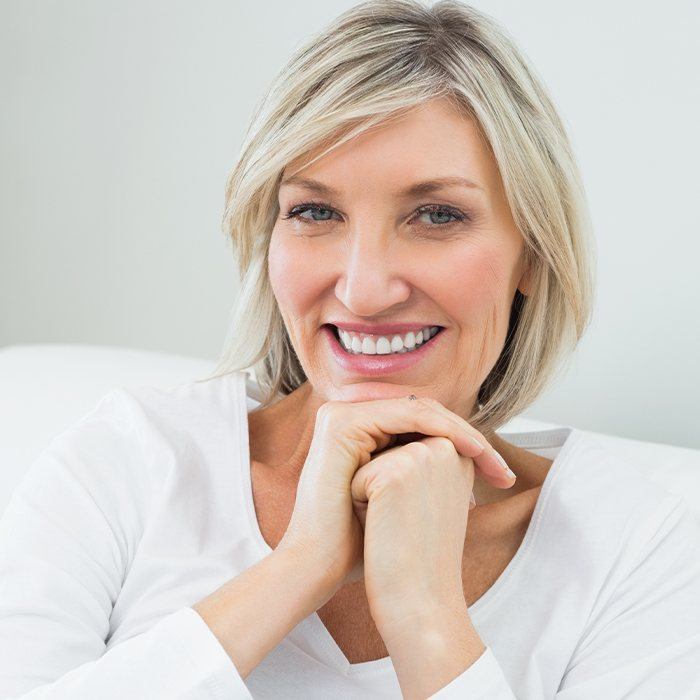 woman in white with hand under chin