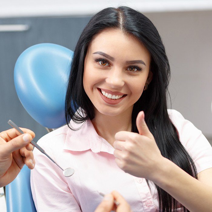 woman doing thumbs up in exam chair