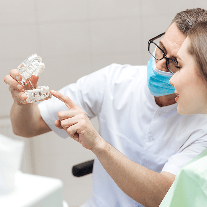 Dentist explaining benefits of dental implants to woman
