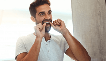 a man with dental implants flossing his teeth