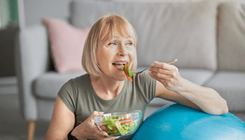 a woman with dental implants eating a healthy meal