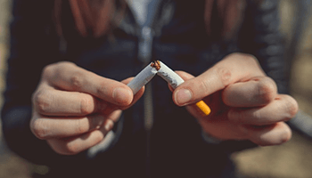 a person breaking a cigarette to protect dental implants