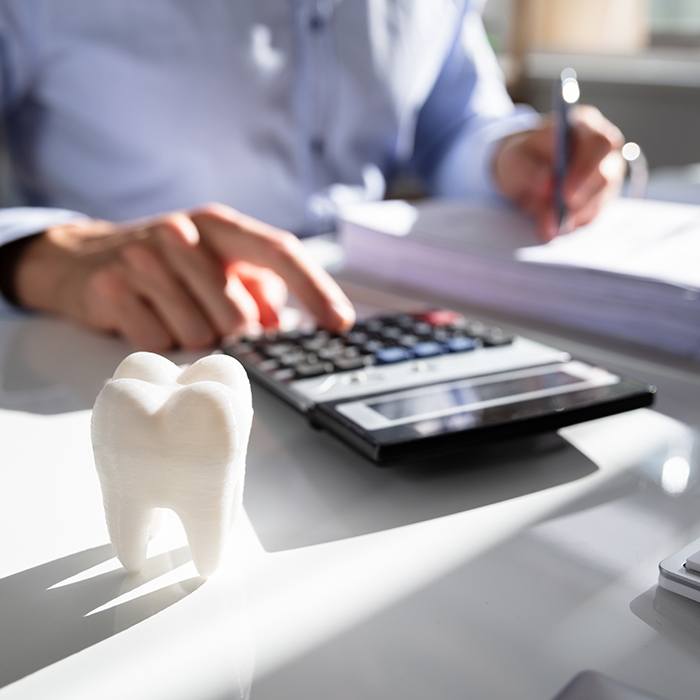 man using calculator by big plastic tooth