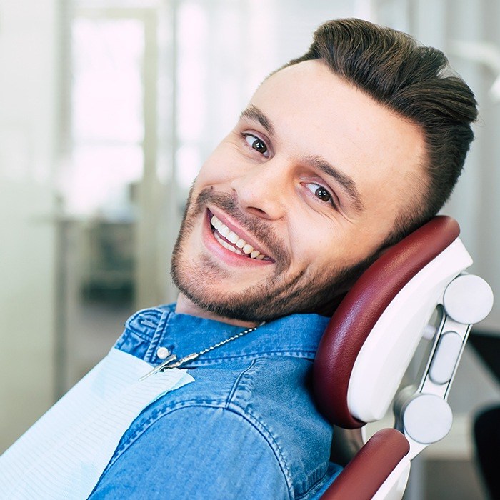 man in jean jacket laying back in exam chair