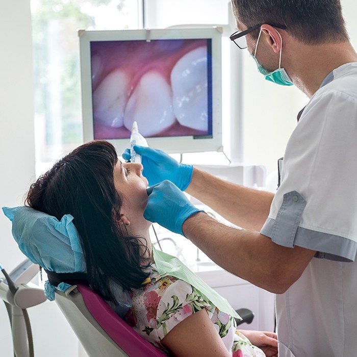 dentist using intraoral camera in woman's mouth