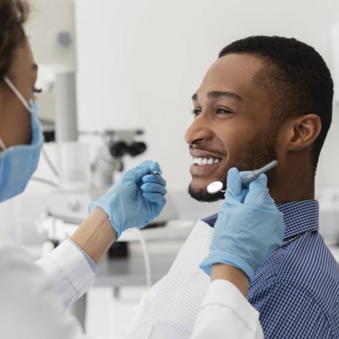 young man sitting in dental chair and smiling at his dentist 