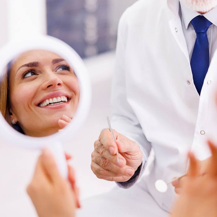 Smiling patient holding handheld mirror