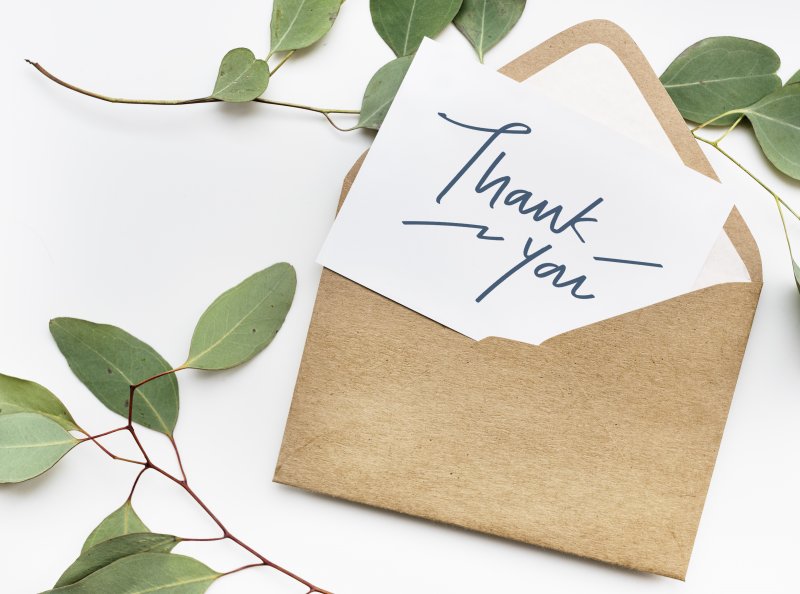 Thank you card and envelope on table with greenery