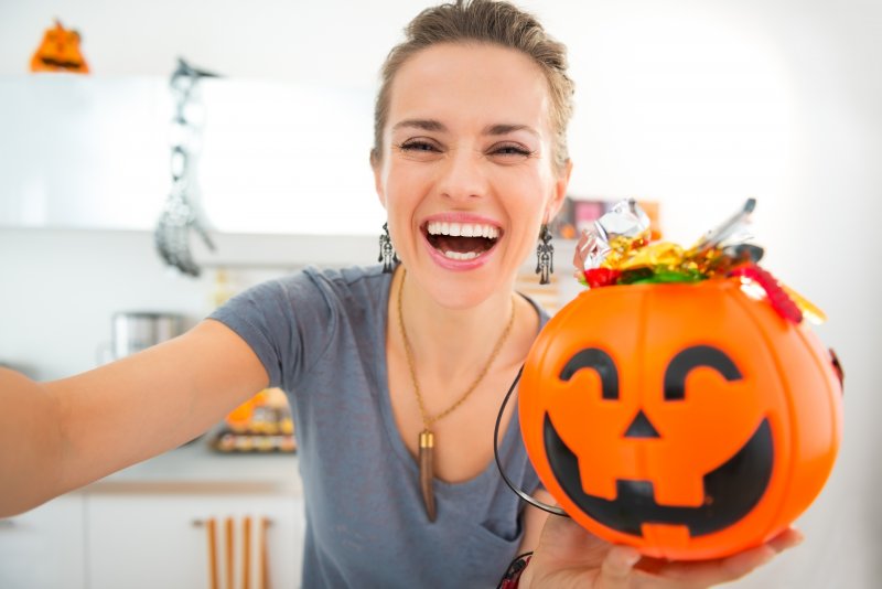 Woman smiling with a bucket of Halloween candy