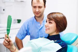 Female patient in dentist’s share looking in mirror