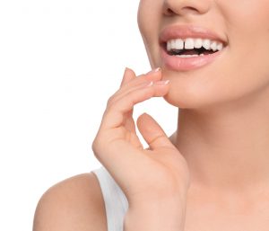 Nose to shoulder view of a woman wearing a white tank top smiling with a gap between her two front teeth